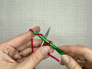 From the slip knot, your yarn should go under and around your needle and then over and across your hook.
