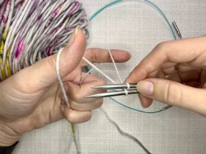 Provisional Cast On Without Crochet Hook: Go under both needles and over the top needle.