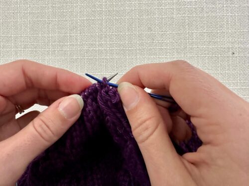 Insert your tapestry needle purlwise the first purl stitch on your knitting needle.